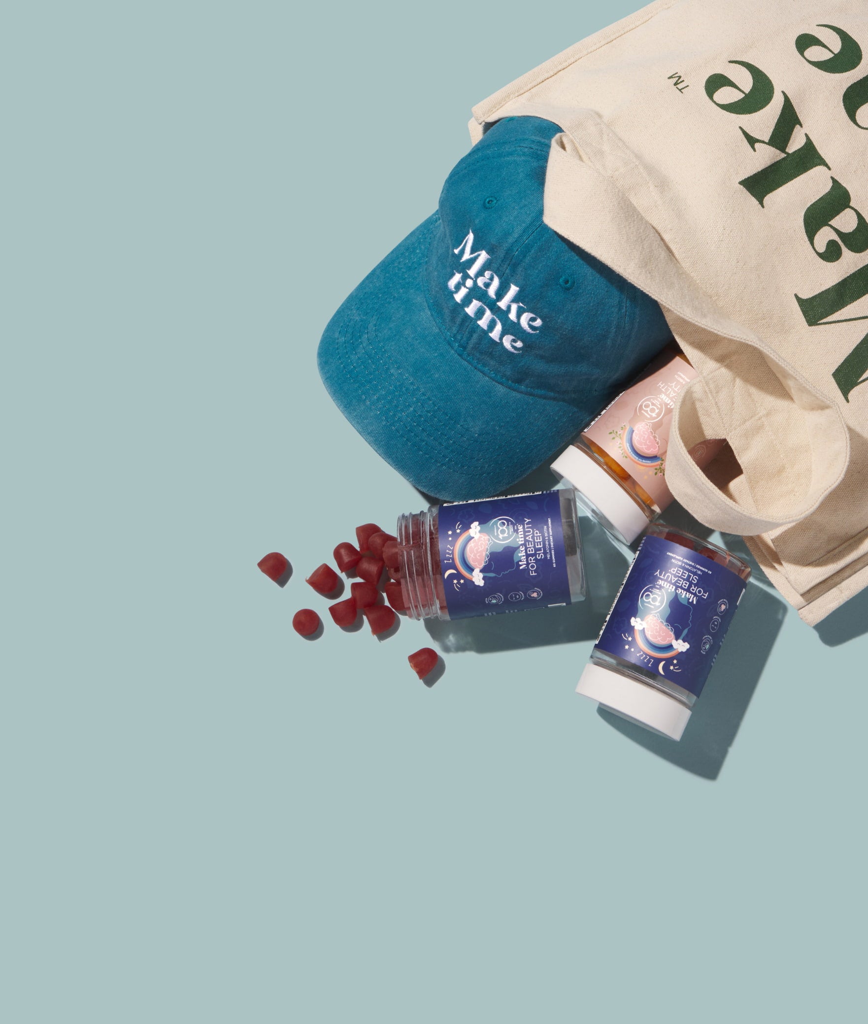 Blue cap with 'Make time' text, small bottles, and a tote bag on a light blue background
