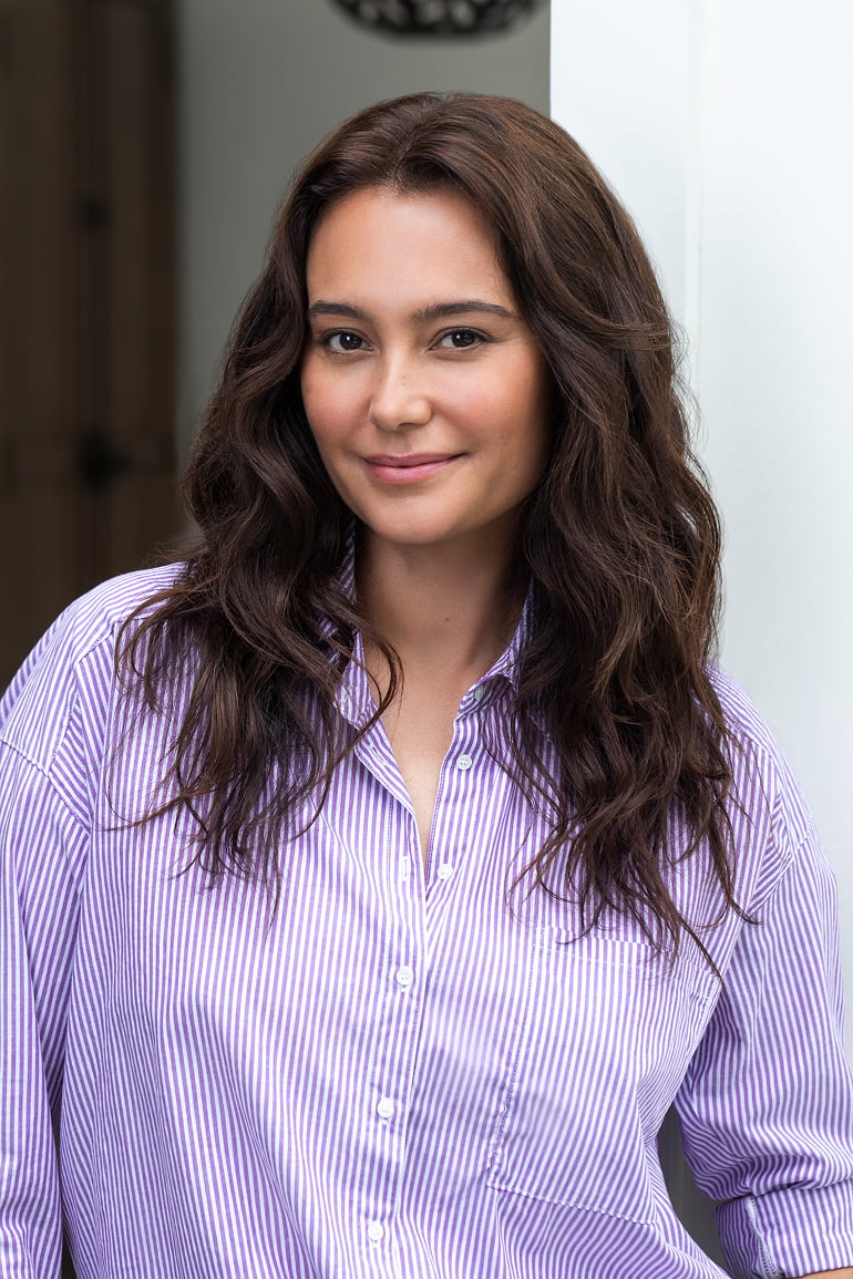 Emma Hemming Willis wearing a purple striped shirt against a white wall