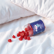 Make Time Beauty Sleep Gummy jar spilling red gummies on white bedsheets