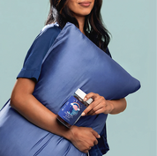 Woman in pajamas holding a pillow and a Make Time Beauty Sleep Gummy jar