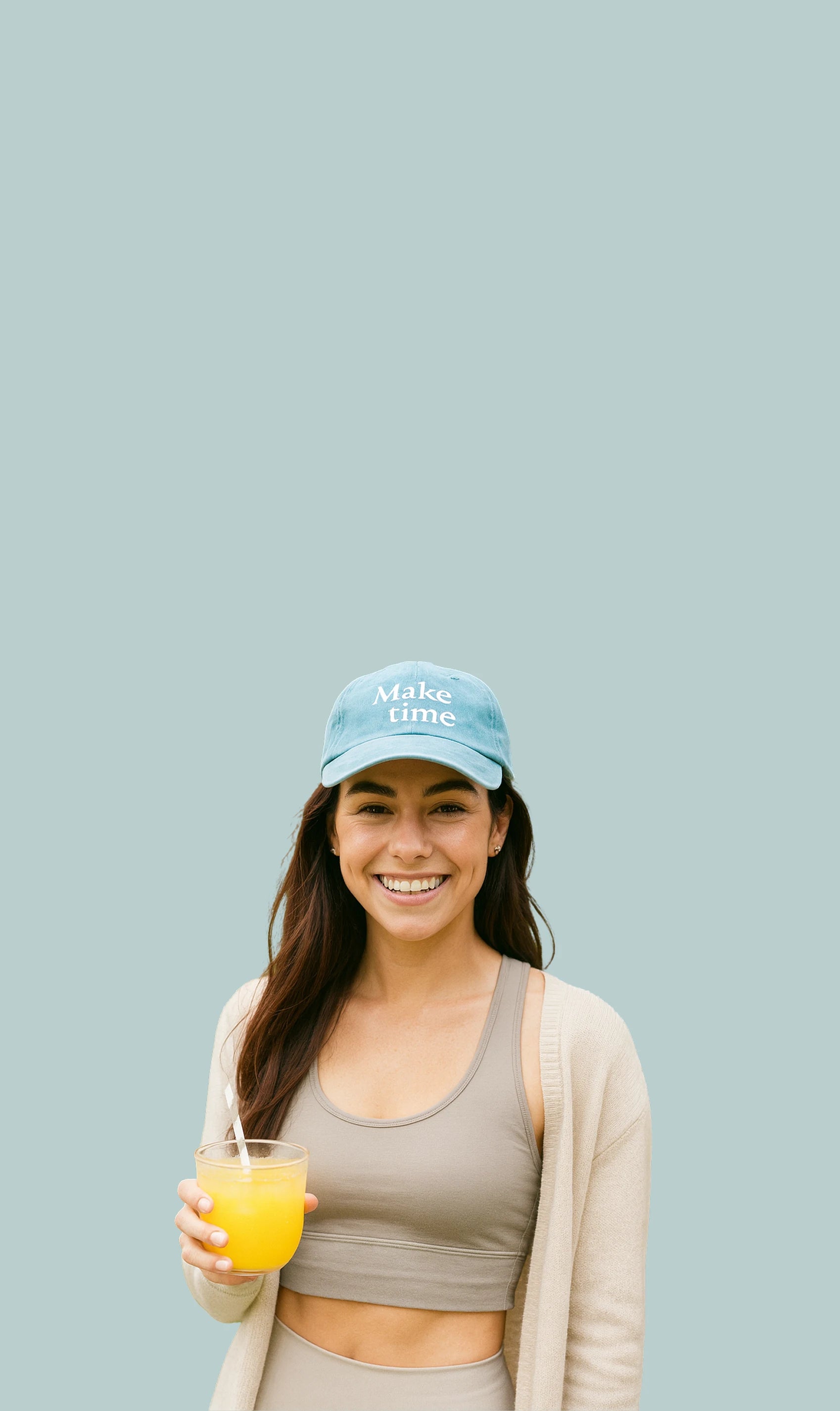 Woman holding a glass of Make Time Wellness BBB Powder wearing a Make Time cap and sports outfit on a light blue background